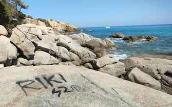 Una scritta nera, forse una
firma con la bomboletta spray, su una roccia di granito davanti
al mare azzurro di Villasimius, lungo la costa sud orientale
della Sardegna, 25 Agosto 2023. ANSA/US GUARDIE AMBIENTALI SARDEGNA