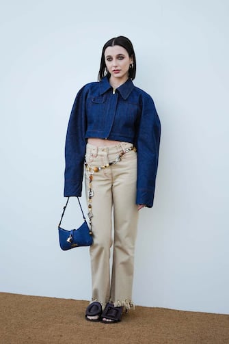 LE BOURGET, FRANCE - DECEMBER 12: Emma Chamberlain wears a blue denim cropped oversized jacket with long sleeves, beige pants with attached long jewelry, a blue suede Jacquemus bag with attached lock, brown leather shoes with geometric patterns, outside the "Le Raphia" Jacquemus show on December 12, 2022 in Le Bourget, France. (Photo by Edward Berthelot/Getty Images)