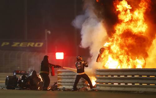 BAHRAIN INTERNATIONAL CIRCUIT, BAHRAIN - NOVEMBER 29: Romain Grosjean, Haas F1, emerges from flames after a horrific crash on the opening lap of the Bahrain Grand Prix, Marshals attend the accident during the Bahrain GP at Bahrain International Circuit on Sunday November 29, 2020 in Sakhir, Bahrain. (Photo by Andy Hone / LAT Images)
