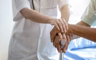 Nurse holding hand of senior man in rest home