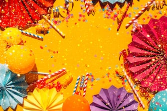 Illuminating yellow festive background with multicolored confetti, colorful paper craft figures, balls and straws and copy space. Trendy colors of the year. Festive concept