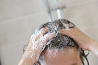 A woman taking a shower and washing her hair.