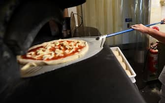 epa09535394 Chef Santosh cooks a pizza at a restaurant a day ahead of their reopening in Elsternwick, Melbourne, Victoria, Australia, 21 October 2021. A further 2,232 local COVID-19 cases and 12 deaths have been reported in Victoria as Melbourne prepares for the end of its sixth lockdown.  EPA/JAMES ROSS  AUSTRALIA AND NEW ZEALAND OUT