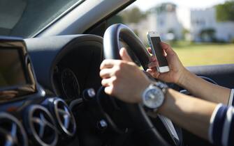 Young woman texting while driving