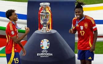 Spain's forward #19 Lamine Yamal and Spain's midfielder #17 Nico Williams celebrate next to the trophy after winning the UEFA Euro 2024 final football match between Spain and England at the Olympiastadion in Berlin on July 14, 2024. (Photo by Odd ANDERSEN / AFP)