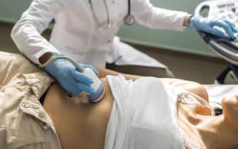 Doctor examining mature woman with ultrasound scanner device
