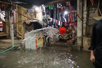 RAWALPINDI, PAKISTAN - AUGUST 14: A man tries to put the flood waters out of his shop after a heavy rain on the eve of Pakistan's Independence Day in Rawalpindi, Pakistan on August 14, 2023. Heavy rains caused flood in low-lying areas in the city that damage to property. (Photo by Muhammad Reza/Anadolu Agency via Getty Images)