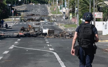 Police patrol a street blocked by debris and burnt out items following overnight unrest in the Magenta district of Noumea, France's Pacific territory of New Caledonia, on May 18, 2024. Hundreds of French security personnel tried to restore order in the Pacific island territory of New Caledonia on May 18, after a fifth night of riots, looting and unrest. (Photo by Delphine Mayeur / AFP) (Photo by DELPHINE MAYEUR/AFP via Getty Images)