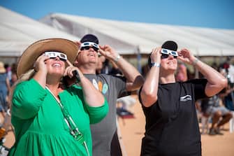 epa10581222 People use solar viewing glasses to look up at the sky ahead of a total solar eclipse at a viewing site 24km from Exmouth, Western Australia, Australia, 20 April 2023. The total solar eclipse will occur on a remote peninsula on the Western Australian coast.  EPA/AARON BUNCH  AUSTRALIA AND NEW ZEALAND OUT