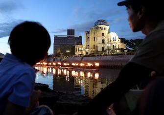 epa10786901 People watch bonfires lightened under the A-bomb Dome to comfort victims of the 1945 atomic bombing at Hiroshima Peace Memorial Park in Hiroshima, Hiroshima Prefecture, western Japan, 05 August 2023 (issued 06 August 2023), the eve of the 78th anniversary of the atomic bombing. Hiroshima City has announced the toll of victims from the atomic bombing rose to about 140,000. The number of victims was counted as the end of 1945 after the August 6 bombing.  EPA/JIJI PRESS JAPAN OUT  EDITORIAL USE ONLY
