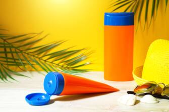 Tubes with mock up sunscreens on the table with yellow summer background. UV protection of the skin with an SPF filter, hair care-shampoo and conditio