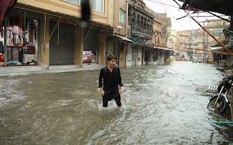 RAWALPINDI, PAKISTAN - AUGUST 14: A man tries to pass a flooded street after a heavy rain on the eve of Pakistan's Independence Day in Rawalpindi, Pakistan on August 14, 2023. Heavy rains caused flood in low-lying areas in the city that damage to property. (Photo by Muhammad Reza/Anadolu Agency via Getty Images)
