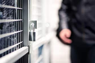 Burglar or thief and storage with lock in basement of condo apartment building. Suspicious man, intruder and criminal. Door with padlock for security.