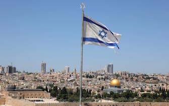 epa10576821 The Israeli flag is backdropped by a general view of the Old City of Jerusalem and the  Dome of the Rock, seen from Mount of Olives in Jerusalem, Israel, 17 April 2023. Israel will celebrate the 75th Independence Day on 26 April.  EPA/ABIR SULTAN