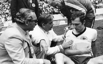 German libero Franz Beckenbauer is treated for a shoulder injury by German team doctor professor Schobert (left) and masseur Erich Deuser (top right) during the 1970 World Cup semifinal Germany against Italy at the Aztec Stadium in Mexico City, Mexico 17 June 1970. Germany lost the game 3-4 against Italy which was scored by Italian midfielder Rivera (not in frame) in the 111th minute. Beckenbauer had sustained the injury to his shoulder at the end of regulation but after a bandage was applied, he had weathered through the two extra time periods of 15 minutes each. (Photo by DB/picture alliance via Getty Images)