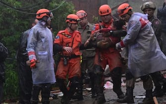 Members of the Civil Defense carry a girl, who remained more than 12 hours under the rubble of her house, which was destroyed by the heavy rains in Petropolis, Brazil on March 23, 2024. At least nine people died in the midst of a strong storm that hits the southeast of Brazil, particularly the mountain area of the state of Rio de Janeiro, where authorities deployed a strong operation this Saturday in the face of a "critical" situation. The authorities reported three deaths in the collapse of a house in the city of Petropolis, about 70 kilometers from the capital of Rio, in a bulletin issued by an emergency committee formed by the government of Rio together with the Fire and Defense forces. (Photo by Pablo PORCIUNCULA / AFP) (Photo by PABLO PORCIUNCULA/AFP via Getty Images)
