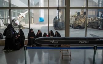 Veiled Iranian schoolgirls sit next to a Paveh Cruise Missile during their visit to Iran's Islamic Revolutionary Guard Corps (IRGC) National Aerospace Park in western Tehran, October 11, 2023. The IRGC National Aerospace Park, showcasing the achievements of the IRGC Aerospace Force, was inaugurated on September 27, 2020, by IRGC Commander-in-Chief Major General Hossein Salami and IRGC Aerospace Force Brigadier General Amir Ali Hajizadeh. In February, the IRGC Aerospace Force commander announced Iran's expertise in guiding solid-propellant missiles beyond the Earth's atmosphere. (Photo by Morteza Nikoubazl/NurPhoto via Getty Images)