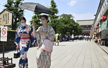 TOKYO, JAPAN - JUNE 30 : Two women wearing a traditional clothe called Yukata, walk at a street leading to Sensoji Temple using an umbrella to protect themselves from the sun on June 30 2022, in Tokyo's famous Asakusa district in Tokyo, Japan. The capital of Japan has been swept by a heat wave for the past few days with temperatures well above 35 degrees Celsius and close to 40 degrees Celsius in some places in Tokyo. (Photo by David Mareuil/Anadolu Agency via Getty Images)