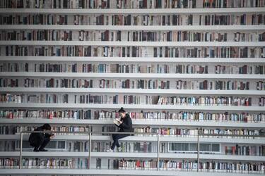 This picture taken on November 14, 2017 shows a woman reading a book at the Tianjin Binhai Library.
A futuristic Chinese library has wowed book lovers around the world with its white, undulating shelves rising from floor to ceiling, but if you read between the lines you'll spot one problem. Those rows upon rows of book spines are mostly images printed on the aluminium plates that make up the backs of shelves. / AFP PHOTO / FRED DUFOUR / To go with AFP story China-library-architecture, FOCUS by Becky Davis        (Photo credit should read FRED DUFOUR/AFP via Getty Images)