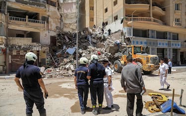 Civil defence first responders speak with a policeman (white) at the scene of a collapsed 13-storey-building in the Sidi Bishr district of Egypt's northern city of Alexandria on June 26, 2023. (Photo by Hazem GOUDA / AFP)