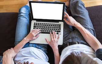 young couple using internet on laptop with empty blank screen at home, top view, buy or rent online concept