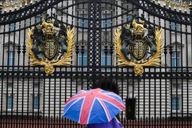 A person with an umbrella picturing the British national flag stands guard in front of Buckingham palace, central London, on September 8, 2022. - Fears grew on September 8, 2022 for Queen Elizabeth II after Buckingham Palace said her doctors were "concerned" for her health and recommended that she remain under medical supervision. The 96-year-old head of state -- Britain's longest-serving monarch -- has been dogged by health problems since last October that have left her with difficulties walking and standing. (Photo by Daniel LEAL / AFP) (Photo by DANIEL LEAL/AFP via Getty Images)