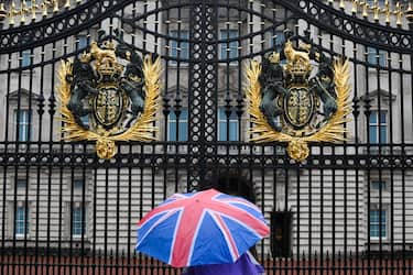 A person with an umbrella picturing the British national flag stands guard in front of Buckingham palace, central London, on September 8, 2022. - Fears grew on September 8, 2022 for Queen Elizabeth II after Buckingham Palace said her doctors were "concerned" for her health and recommended that she remain under medical supervision. The 96-year-old head of state -- Britain's longest-serving monarch -- has been dogged by health problems since last October that have left her with difficulties walking and standing. (Photo by Daniel LEAL / AFP) (Photo by DANIEL LEAL/AFP via Getty Images)