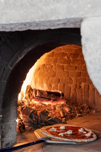 Pizzas cooked in outdoor wood fired pizza oven, at Borgo Pignano, Tuscany, Italy