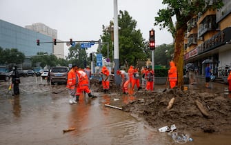 epa10779146 Workers remove mud from a road during a downpour in Mentougou District, west of Beijing, China, 01 August 2023. Heavy rains brought by Typhoon Doksuri caused floods in northern China and left two dead and thousands being evacuated as Beijing experienced its heaviest rainfall of the year.  EPA/MARK R. CRISTINO