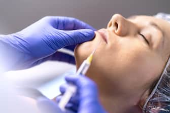 Lip injection, augmentation and enhancement in plastic surgery clinic with needle and syringe. Woman having cosmetic treatment.