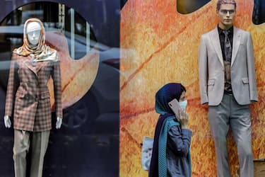 A woman walks past a clothing shop window showing mannequins displaying formal wear, in the north of Iran's capital Tehran on September 7, 2022. - After the fall of the shah in 1979, the Iranian clergy who came to power with Ayatollah Khomeini banned the wearing of neckties because in their eyes they symbolised a subjection to Western culture. Today, ministers, senior civil servants or heads of state-owned companies wear under their suits a shirt with a buttoned, open or Mao collar. (Photo by AFP) (Photo by -/AFP via Getty Images)