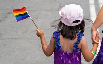 Montreal, CA - 14 August 2016: A young girl is holding a gay rainbow flag as she holds her mother's hand