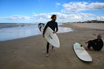 A view taken on May 11, 2020 shows surfers on a beach of the Adriatic coast in Rimini, northeastern Italy, during the country's lockdown aimed at curbing the spread of the COVID-19 infection, caused by the novel coronavirus. - With the tourism sector reeling, the European Commission was on May 13, 2020 to present a rescue plan for the sector. (Photo by Vincenzo PINTO / AFP) (Photo by VINCENZO PINTO/AFP via Getty Images)