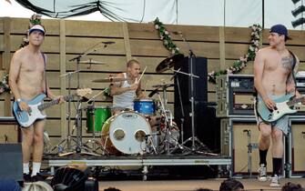 (L-R) American singer, musician, songwriter, and record producer Mark Hoppus, American drummer Travis Barker and American musician, singer, songwriter, author, record producer, actor, and filmmaker Tom DeLonge, of the American rock band Blink-182, perform on stage during the KROQ Weenie Roast on June 19, 1999 at the Irvine Meadows Amphitheatre in Irvine, California. (Photo by Lester Cohen/Getty Images)