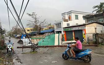 Local residents ride their motorcycle past broken utility pole in Sittwe, in Myanmar's Rakhine state, on May 15, 2023, after cyclone Mocha made a landfall. Cyclone Mocha made landfall between Cox's Bazar in Bangladesh and Myanmar's Sittwe carrying winds of up to 195 kilometres (120 miles) per hour, the biggest storm to hit the Bay of Bengal in more than a decade. (Photo by Sai Aung MAIN / AFP) (Photo by SAI AUNG MAIN/AFP via Getty Images)