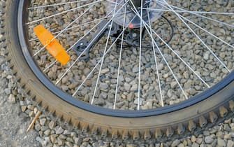 bike wheel close-up with orange light reflector on the stone background. Bicycle detail. Flat tyre