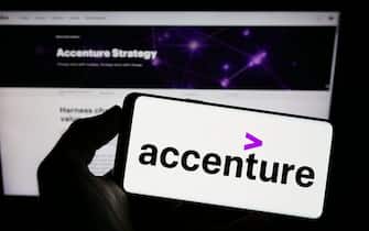 Person holding smartphone with logo of information technology company Accenture plc on screen in front of website. Focus on phone display.