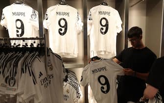 A man holds the newly launched jersey of French footballer Killyan Mbappe at the Real Madrid's official store in the Santiago Bernabeu stadium in Madrid on July 11, 2024. (Photo by Pierre-Philippe MARCOU / AFP) (Photo by PIERRE-PHILIPPE MARCOU/AFP via Getty Images)