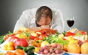 Man sleeping at table with much food