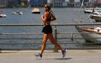 epa08571272 A woman is seen jogging along Battery Park a in New York City, USA, 28 July 2020. Temperatures are forecasted to reach 91 degrees Fahrenheit (33 degrees Celsius) in New York City on 28 July.  EPA/JASON SZENES