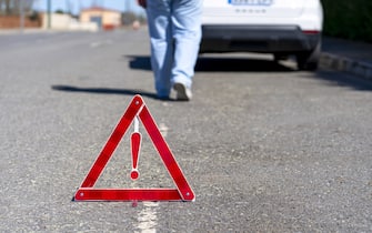 A warning triangle behind a car on the side of a road