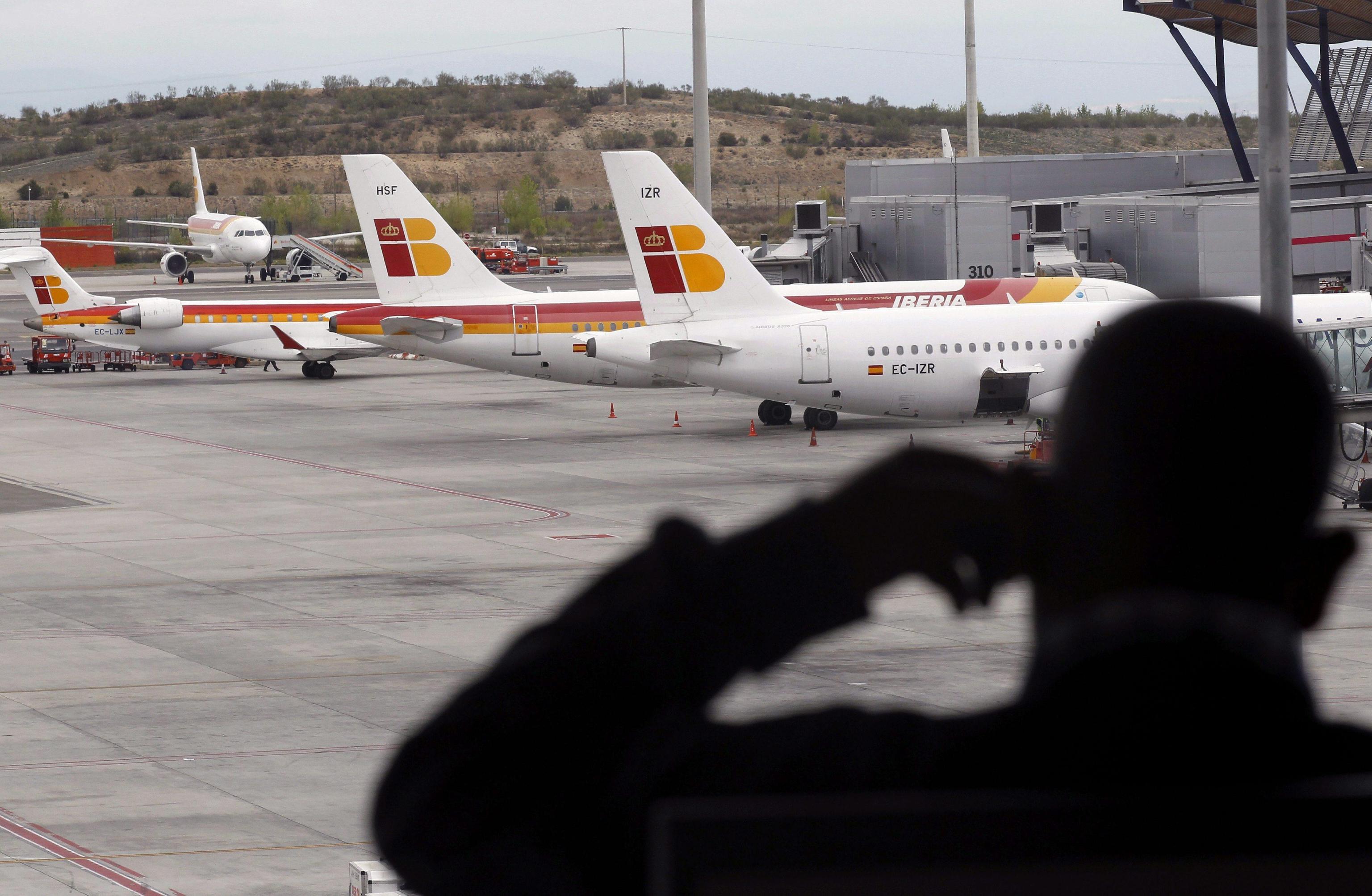 epa03198378 A traveller looks at the planes at Madrid-Barajas International Airport's Terminal 4 in Madrid, Spain, 27 April 2012. Iberia's pilots called off the strike to protest against the the launching of Iberia's low cost subsidiary airline Iberia Express after the Spanish government establish an obligatory arbitration between Iberia and labor union Sepla.  EPA/CHEMA MOYA