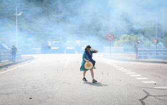A protester walks near tear gas smoke  during a demonstration against the construction of a high-speed rail line between Lyon and Torino, in La Chapelle, near Modane, in the French Alps' Maurienne valley, on June 17, 2023. Hundreds of oponents to the Lyon-Torino high-speed rail line demonstrated on June 17 despite a ban on the gathering, of which the details are yet to be determined and despite a heavy police presence in the valley. They set up a makeshift camp on land lent by the municipality of La Chapelle, outside the ban zone announced the day before by the Savoie prefecture. (Photo by OLIVIER CHASSIGNOLE / AFP) (Photo by OLIVIER CHASSIGNOLE/AFP via Getty Images)