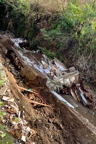 Una ventina di bare e 80 urne sono finite in un torrente in seguito al cedimento di un'ala del cimitero. È accaduto a S. Agata dei Goti, in provincia di Benevento, 19 gennaio 2023. 
ANSA