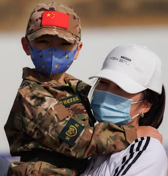 epa10662673 A mother holding a child in a PLA (People's Liberation Army) uniform watches before launch of the Long March-2F carrier rocket with a Shenzhou-16 manned space flight at the Jiuquan Satellite Launch Centre, in Jiuquan, Gansu province, China, 30 May 2023. The Shenzhou-16 manned space flight mission will transport three Chinese astronauts to the Tiangong space station.  EPA/ALEX PLAVEVSKI