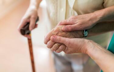 Nurse consoling her elderly patient by holding her hands