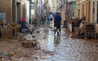 Residents try to clean their houses as the street is covered in mud on October 31, 2024 after flash floods affected the town of Alfafar, in the region of Valencia, eastern Spain. Rescuers raced on October 31, 2024 to find survivors and victims of once-in-a-generation floods in Spain that killed at least 95 people and left towns submerged in a muddy deluge with overturned cars scattered in the streets. About 1,000 troops joined police and firefighters in the grim search for bodies in the Valencia region as Spain started three days of mourning. Up to a year's rain fell in a few hours on the eastern city of Valencia and surrounding region on October 29 sending torrents of water and mud through towns and cities. (Photo by JOSE JORDAN / AFP)