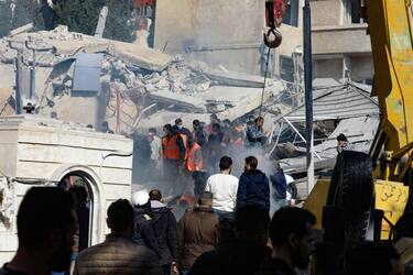 People and rescuers gather in front of a building destroyed in a reported Israeli strike in Damascus on January 20, 2024. An Israeli strike on Damascus killed five people in a building where "Iran-aligned leaders" were meeting on January 20, a war monitor said, as regional tensions soar over the Israel-Hamas war. (Photo by Louai Beshara / AFP) (Photo by LOUAI BESHARA/AFP via Getty Images)