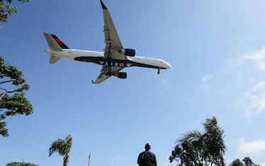 LOS ANGELES, CA - JULY 12:  A man watches as a Delta Air Lines plane lands at Los Angeles International Airport on July 12, 2018 in Los Angeles, California. Delta announced today that it will increase fares by reducing the supply of seats in an effort to offset higher fuel prices.  (Photo by Mario Tama/Getty Images)