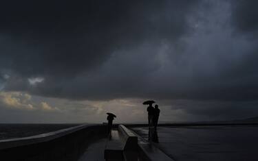 People stand under umbrella's as they look out towards the Mediterranean sea during heavy rain in the French riviera city of Nice on March 3, 2024. (Photo by Valery HACHE / AFP) (Photo by VALERY HACHE/AFP via Getty Images)